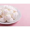 Petites meringues natures dans une assiette sur un fond rose